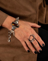 Chunky silver-plated bracelet with a large amber crystal, paired with a silver ring, styled on a woman's wrist.