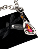 Chunky silver-plated necklace with a red crystal pendant, displayed on a black suede pouch with a tied ribbon.