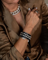 Silver plated unisex cuff bracelet featuring an open bangle design, worn with black and silver layered bracelets.