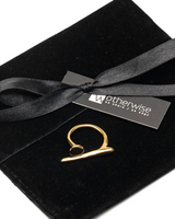Gold asymmetrical statement ring displayed on a black suede pouch with a ribbon, showcasing its contemporary design.