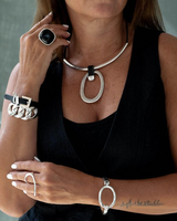 Chunky black leather choker featuring a large silver geometric circle pendant, styled with additional silver jewelry.