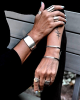 Chunky minimalist metallic cuff set featuring a wide flat cuff and an open double band cuff, worn on a model's arms.