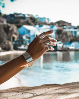 Chunky minimalist metallic cuff set featuring a wide flat bangle and an open double band, displayed on a hand.