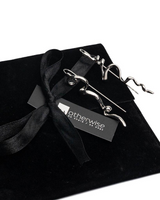 Abstract mismatched zinc drop earrings showcased in an elegant black suede pouch with a ribbon, featuring unique irregular shapes.