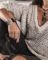 Wide leather cuff bracelet featuring soft black leather and silver-plated Zamak bars, worn on a model's wrist with rings.