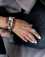 Triple wrap bracelet featuring brown genuine leather and a silver metal cuff, worn on a wrist with a silver ring.