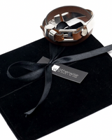 Triple wrap bracelet in brown leather and sterling silver, featuring a chunky metal cuff and magnetic closure, displayed on a black pouch.