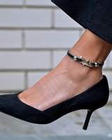 Chunky black leather anklet featuring a sterling silver plated shark charm, worn with a black pointed toe heel.