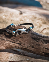 Chunky black leather anklet featuring a sterling silver plated shark charm and silver beads, set on a wooden surface.