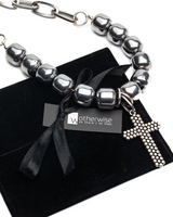 Three-piece hematite leather choker set with silver beads and a textured cross, presented in a black suede pouch.