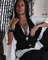 Long chunky heart ball chain necklace features a sculpted heart pendant and oversized metal ball chain, styled with a black vest.