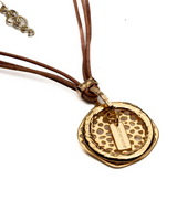 Natural leather strands with a hammered gold-plated hoop create a unique, edgy necklace design.