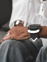 Wide black leather cuff bracelet featuring a large silver buckle, worn on a model’s wrist over a casual outfit.