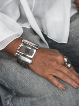 Chunky statement bracelet with large zamak slider bars and flat brass chain, plated in antique silver, worn on a wrist.