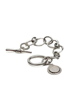 Silver bracelet featuring an asymmetric link chain, large T-bar toggle closure, and a teardrop Phaistos Disc pendant.
