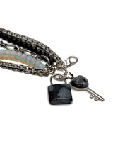 Five-strand bracelet featuring moonstone and black glass beads, with a lock and key charm in stainless steel.