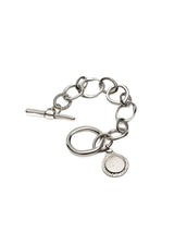 Silver Phaistos Disc Bracelet featuring asymmetrical links and a Zamak teardrop pendant with a T-bar toggle closure.