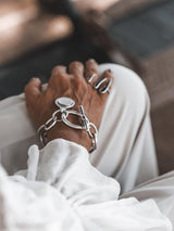 Silver bracelet with asymmetric link chain, featuring a teardrop pendant displaying the Phaistos Disc.