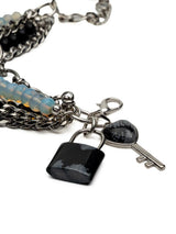 Five-strand bracelet featuring moonstone and black glass beads, stainless steel chains, with lock and key charm details.