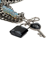 Five-strand bracelet featuring blue glass beads, black agate lock, and key pendant on a stainless steel chain.