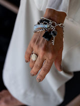 Five-strand bracelet featuring moonstone, black glass beads, and a lock and key charm, worn on a model's wrist.