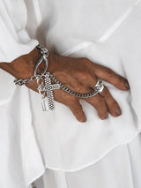 Stainless steel chain bracelet with a large gothic cross pendant, worn over a hand, paired with an adjustable silver ring.
