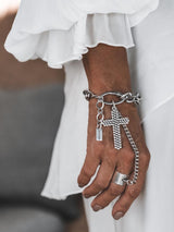 Gothic cross hand chain bracelet with a large cross pendant and adjustable silver ring, worn on a woman's hand.