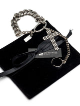 Stainless steel hand chain bracelet with a large gothic cross pendant, presented on a black velvet pouch with a ribbon.