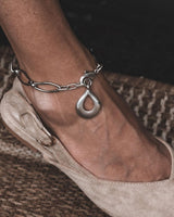Stainless Steel Teardrop Anklet featuring a wavy oval link chain and a smooth teardrop pendant, worn on a bare ankle.