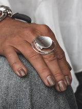 Adjustable sterling silver ring featuring a large, irregular circle with a sleek finish, worn on a hand against denim.