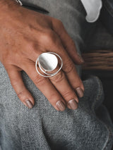 Adjustable sterling silver ring featuring a large, irregular circle with a modern geometric design, worn on a hand against denim.