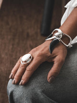 Adjustable sterling silver ring with a large, irregular circle design, worn on a hand resting on gray jeans.