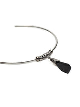 A silver-toned metal wire headband with a textured cylindrical bead and a dangling black faceted stone charm, shown on a plain white background.