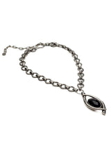 A silver-toned chain necklace featuring a unique teardrop-shaped pendant with a smooth, polished black center, displayed on a clean white background.