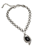 A silver-toned chain necklace featuring a stylized eye-shaped pendant with a glossy black oval center, displayed on a clean white background.