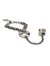 A silver-toned metal bracelet featuring a central interlocking double-ring disc, a curb chain link section, and a wide open cuff clasp, shown on a plain white background.