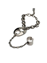 A silver-toned metal bracelet featuring a central oval link with a cutout, connected by a chain to a ring-shaped charm and a small rectangular clasp, shown on a plain white background.
