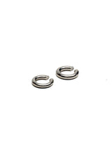 Asymmetric metal ear cuffs in silver, featuring a bold larger and a minimalist smaller design for a modern look.