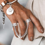 Connected Chevalier Ring Set features two wide brass bands linked by an antique silver chain, adorned with round charms.
