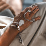 Connected Chevalier Ring Set featuring two wide brass bands linked by an antique silver chain, adorned with round charms.