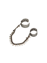 Double pinky ring set with intricate brass bands linked by a 4-inch antique silver chain, accented by round charms.