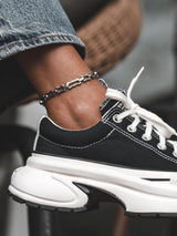 Chunky stainless steel rectangular link anklet, worn on ankle above black sneaker, features a minimalist design and casual vibe.