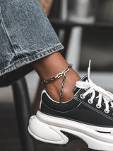 Stainless steel rectangular link chain anklet worn on ankle, featuring a bold, minimalist design with waterproof properties.